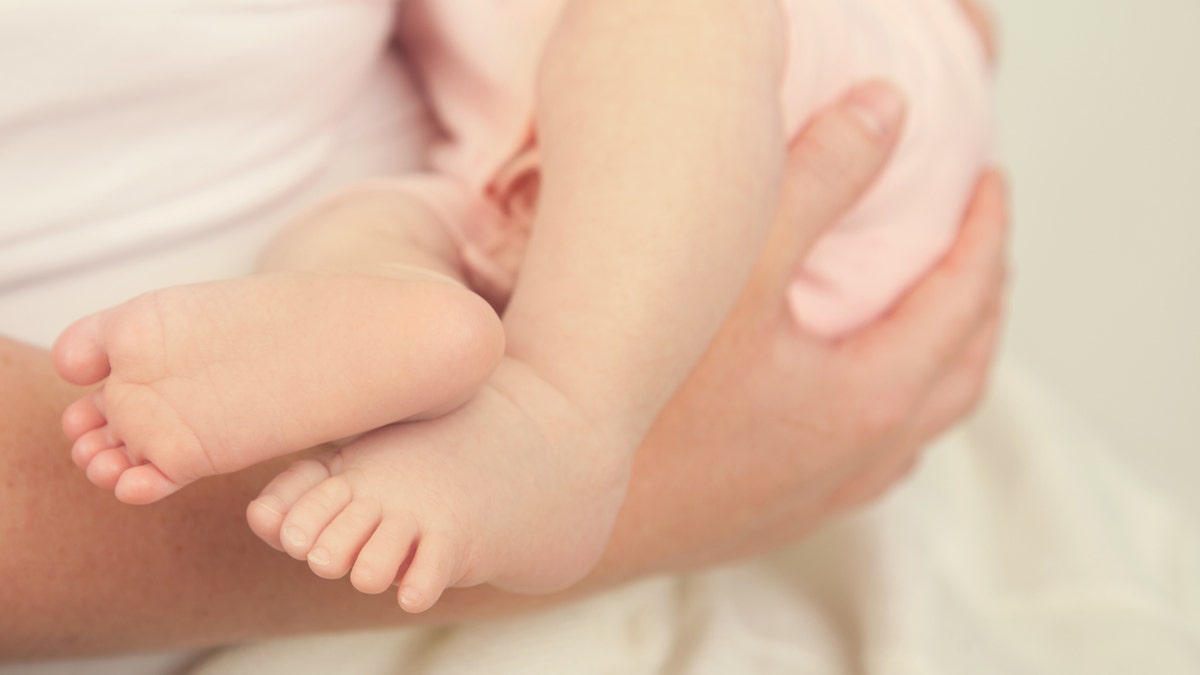 Baby's feet of girl who leaves a mother